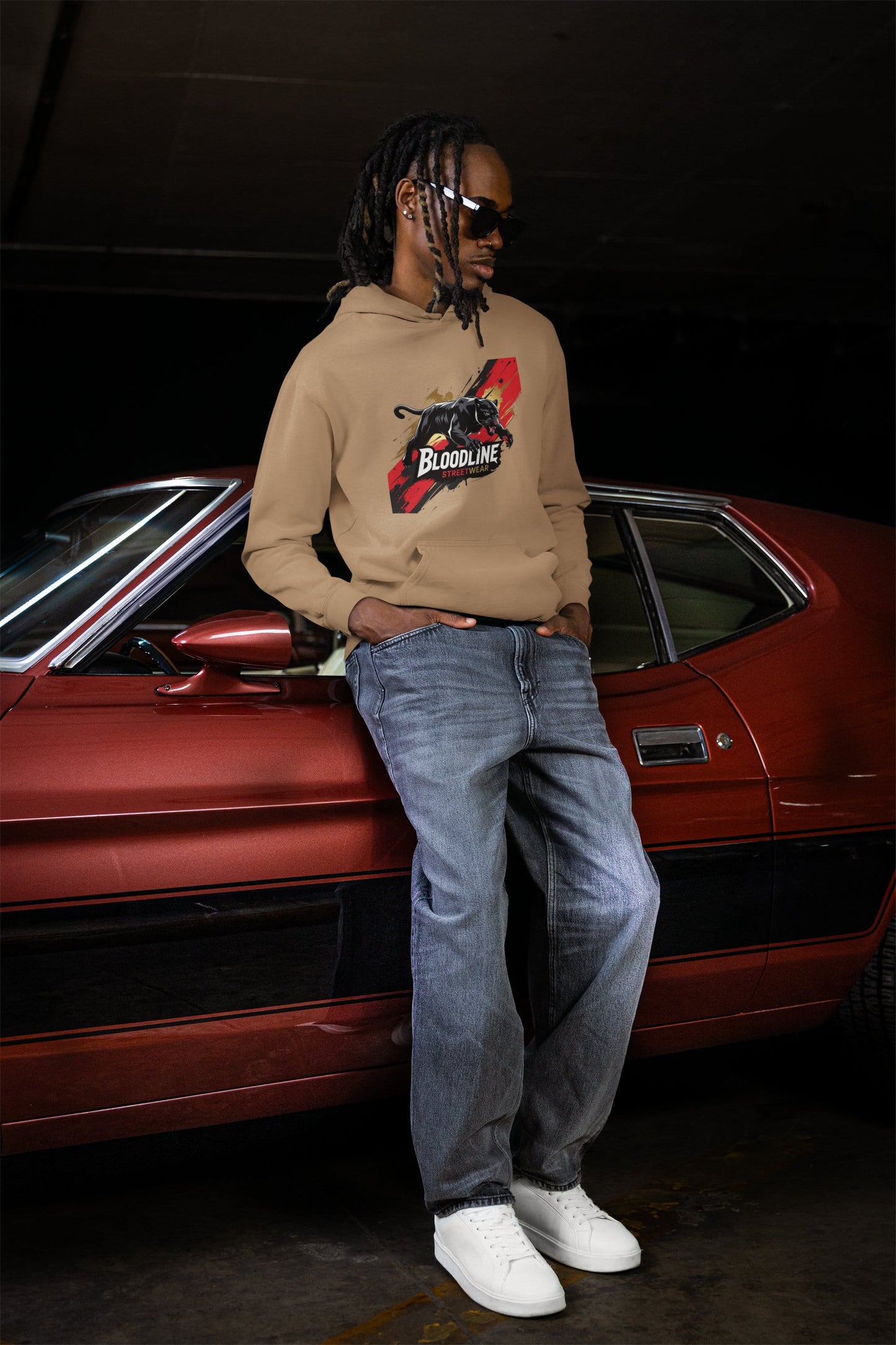 Person wearing a hoodie with a graphic design in front of a red car