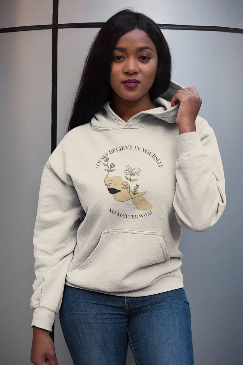 Person wearing a beige hoodie with a motivational quote and sloth graphic against a gray background