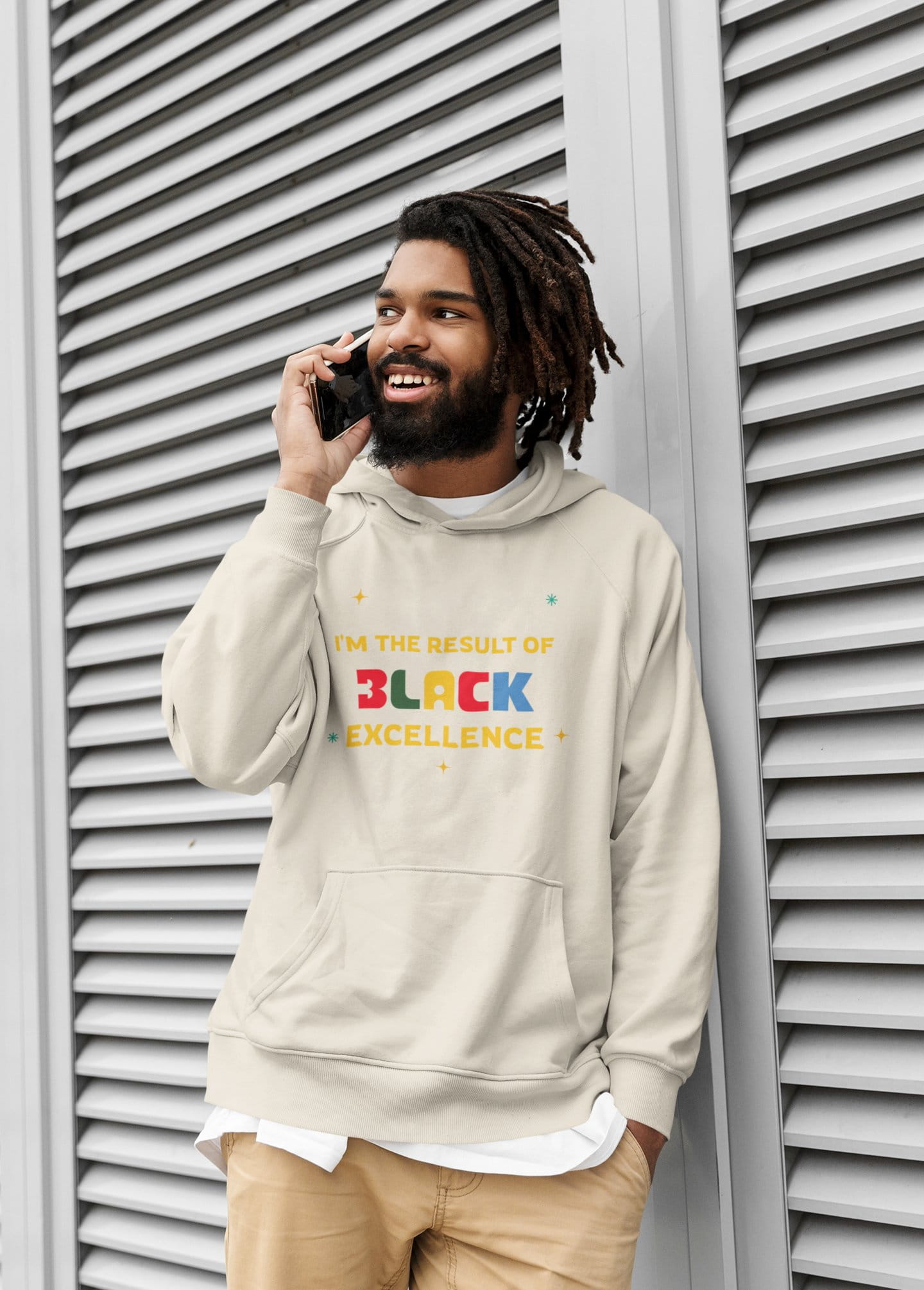 Man wearing a hoodie with 'Black Excellence' text, standing against a textured wall.