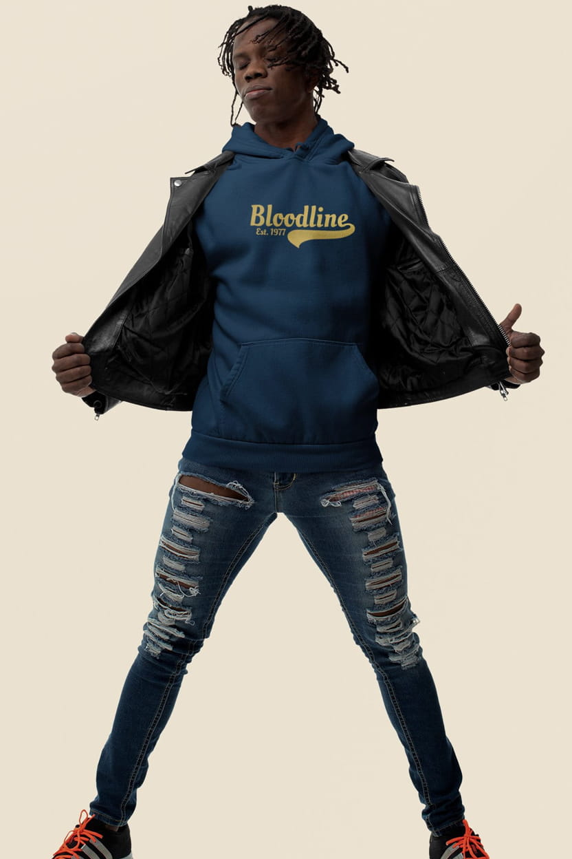 Person wearing a blue hoodie with 'Bloodline' logo and ripped jeans on a beige background