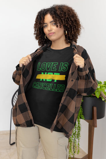 Woman wearing a black t-shirt with 'LOVE IS NOT CANCELLED' text, holding a plaid jacket.