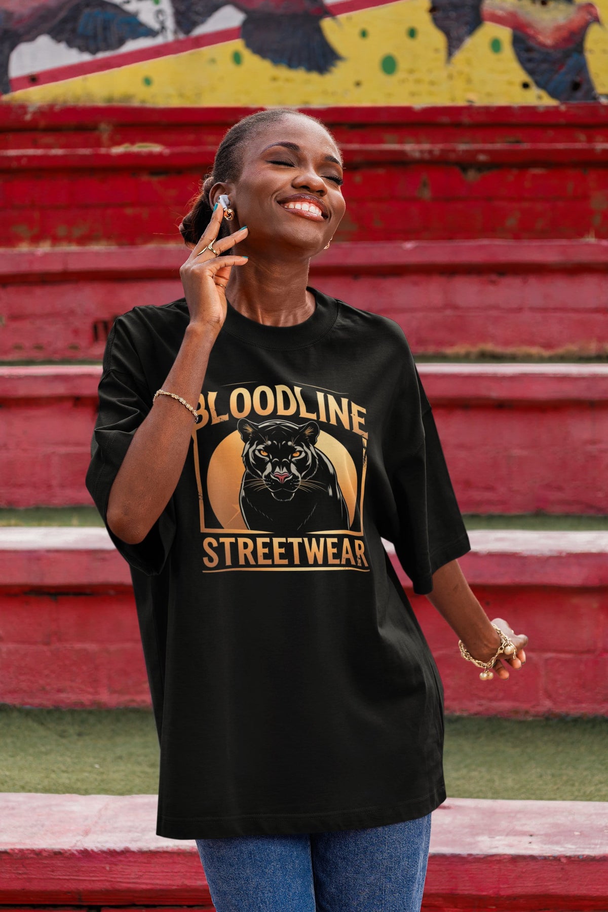 Woman wearing a black 'Bloodline Streetwear' t-shirt in front of red steps.