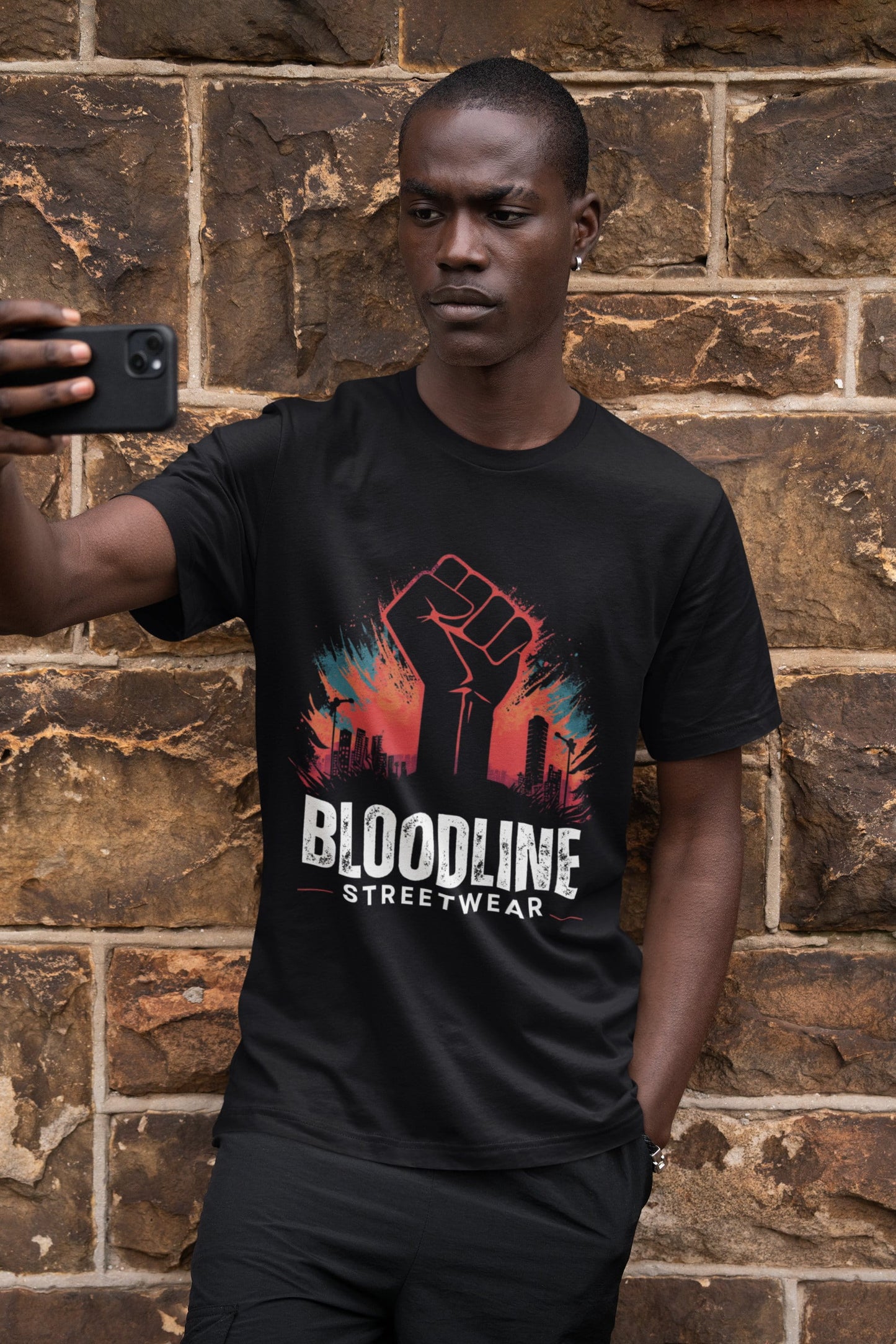 Person wearing a black t-shirt with 'Bloodline Streetwear' design against a brick wall.