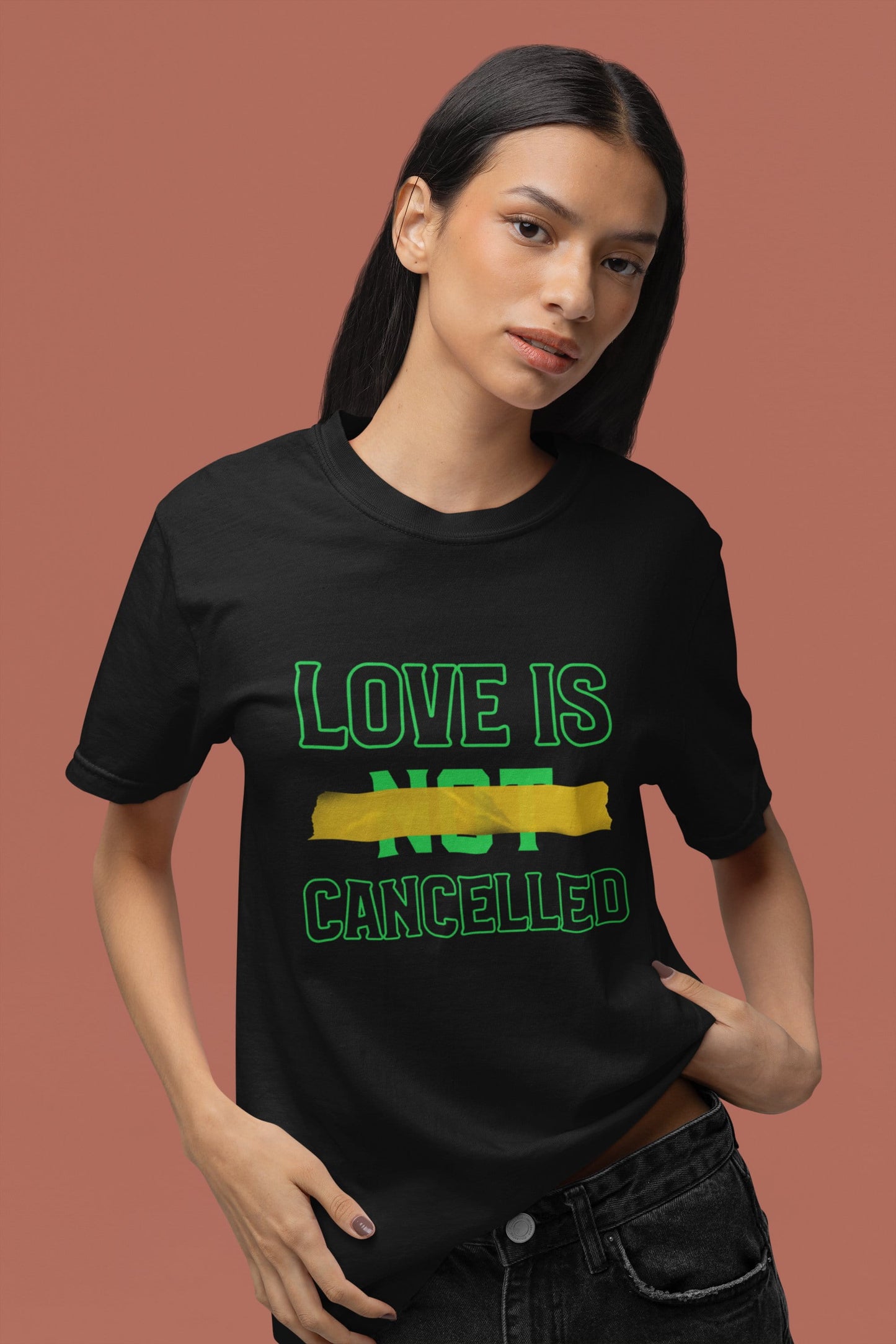 Person wearing a black t-shirt with 'LOVE IS NOT CANCELLED' text on a brown background