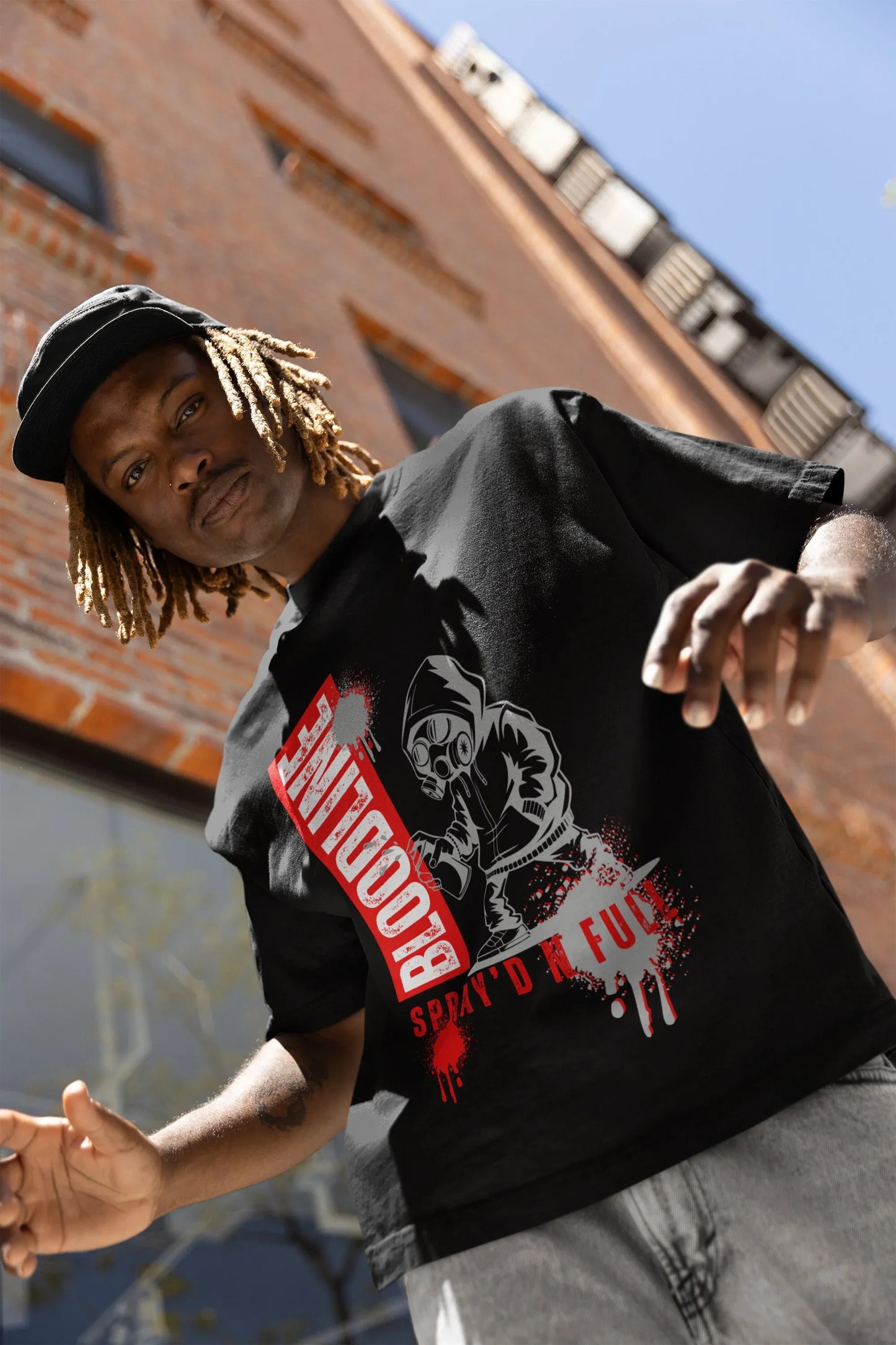 Person wearing a black t-shirt with graphic design and text, standing against an urban background.