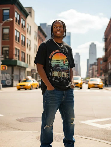A man standing on a city street wearing a black graphic t-shirt with a colorful sunset design