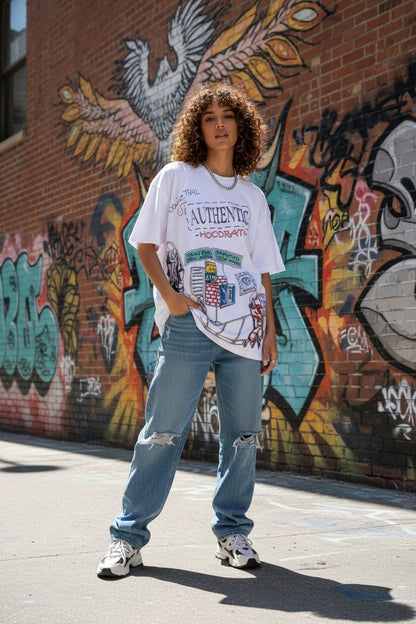 Person wearing a white graphic t-shirt and blue jeans standing in front of a colorful graffiti wall.