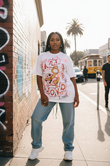 Female model wearing Can't B Lokd SouLethal Hand-Painted Tee by Bloodline Streetwear on a graffiti street with palm trees