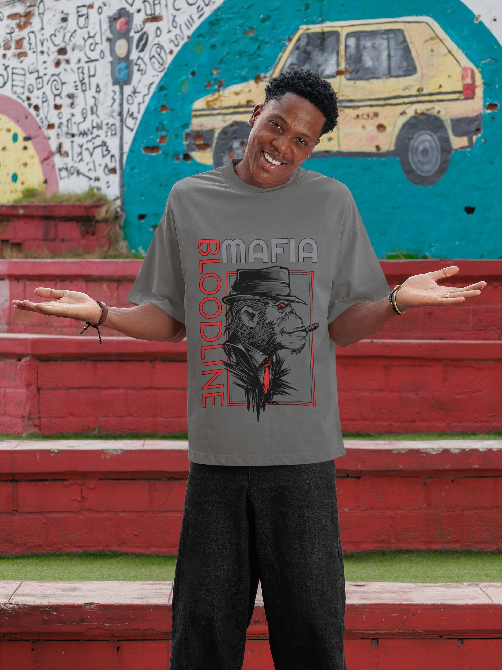 Person wearing a gray t-shirt with a graphic design in front of a colorful mural.