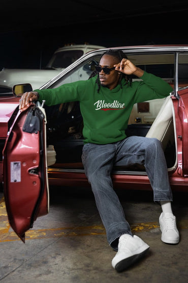 Person wearing a green 'Bloodline' hoodie sitting in a red car.