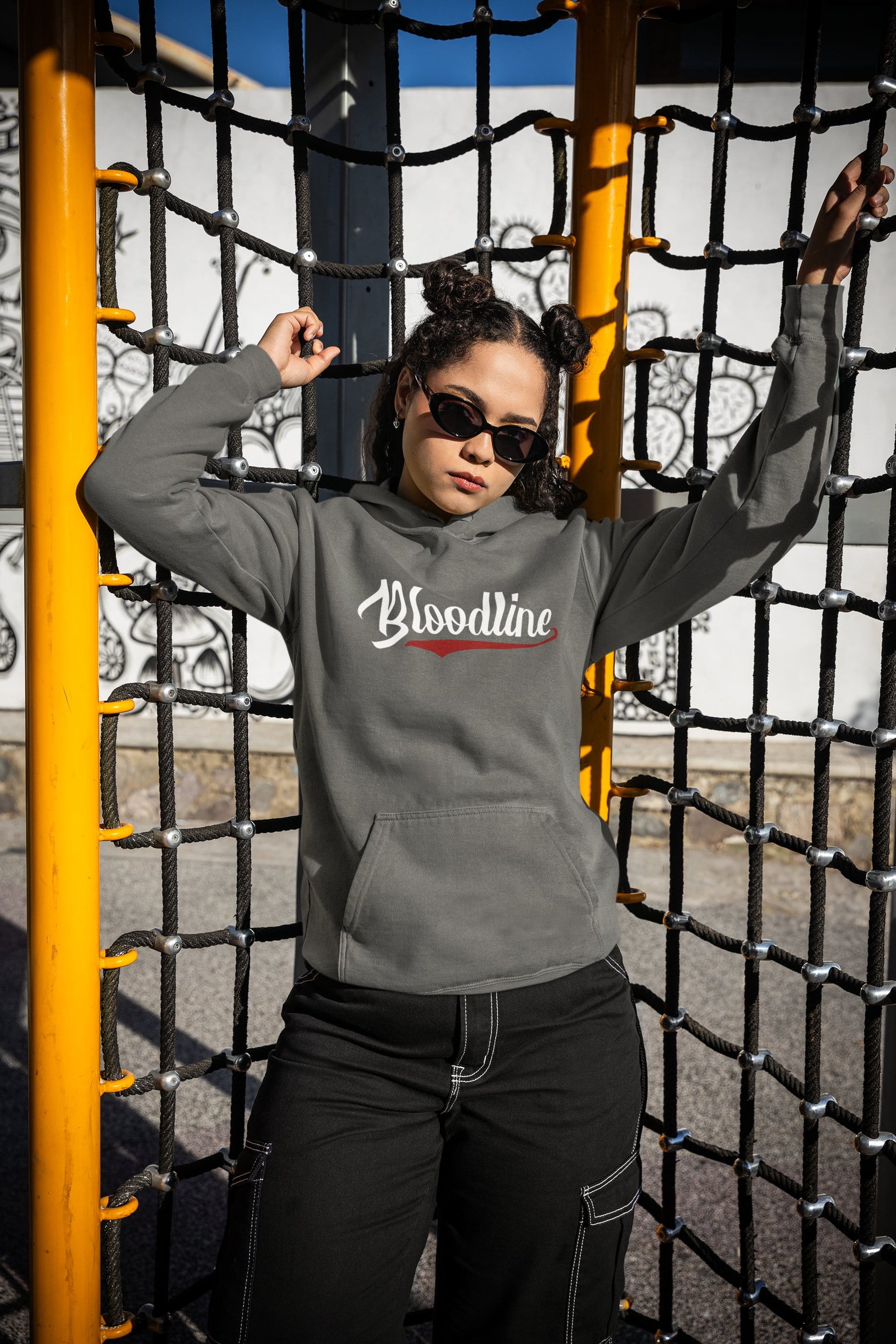 Person wearing a gray hoodie with 'Bloodline' text, standing in front of playground equipment.