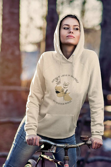 Person wearing a beige hoodie with a printed design, standing outdoors.