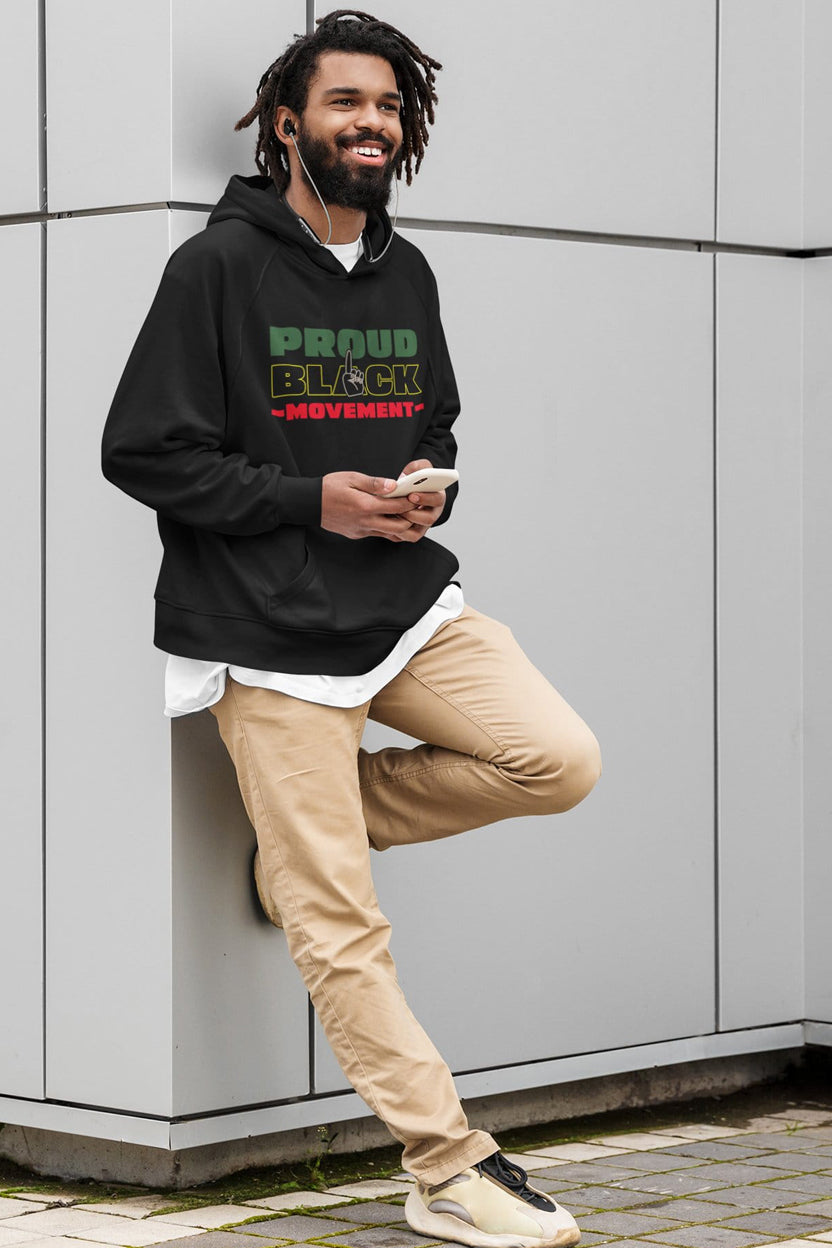 Man wearing a black hoodie with 'Proud Black Movement' text, standing against a gray wall.