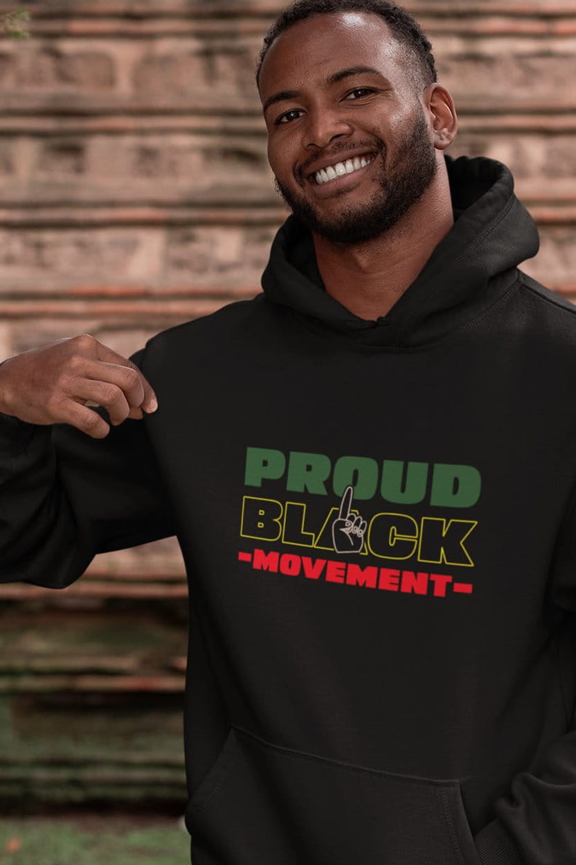 Man wearing a black hoodie with 'Proud Black Movement' text against a brick wall.