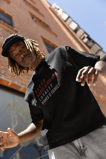 Man wearing a black hoodie with text, standing against a brick wall.