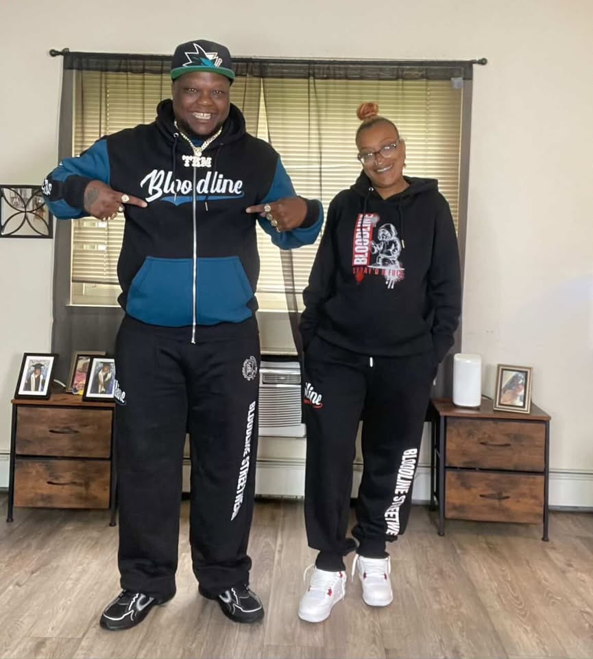 Two people wearing matching sweatshirt sets in a room with wooden furniture and framed pictures.