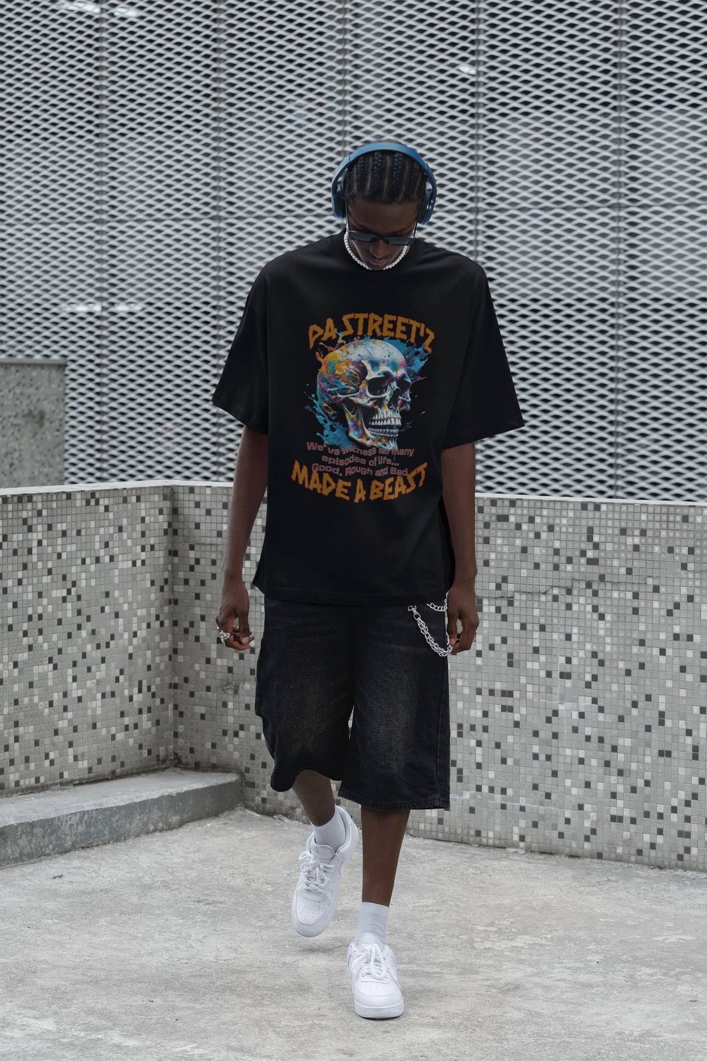 Person wearing a black graphic t-shirt and shorts walking against a textured wall.