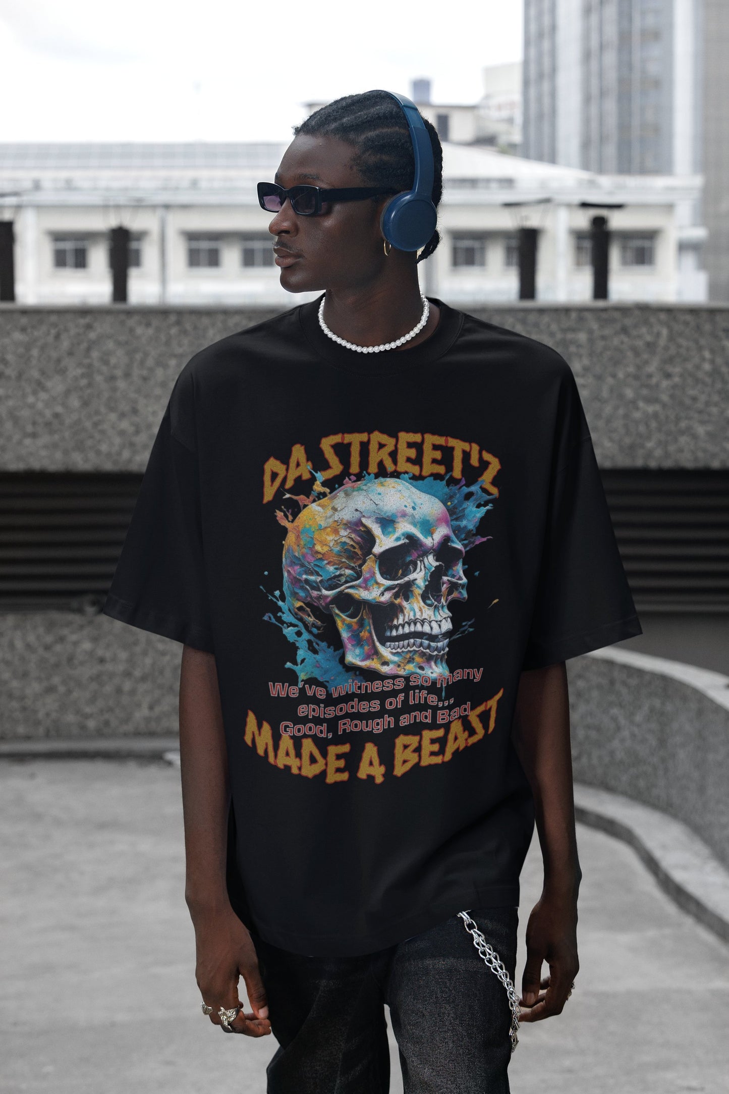 Person wearing a black t-shirt with a colorful skull design and text, standing outdoors.