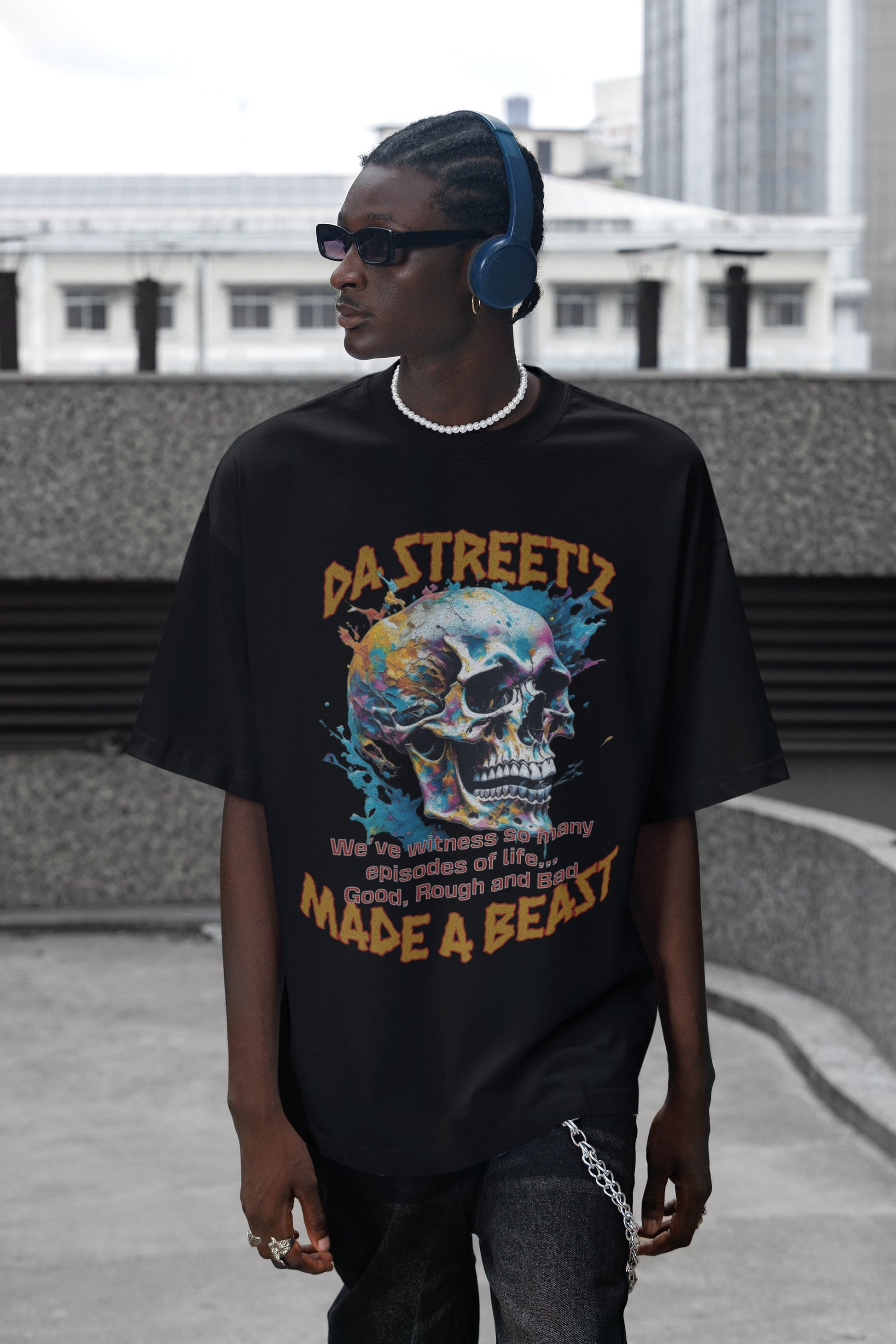 Person wearing a black t-shirt with a colorful skull design and text, standing outdoors.