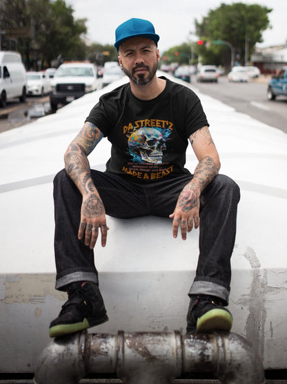 Man sitting on a car with tattoos and a beard, wearing a black t-shirt and blue cap.