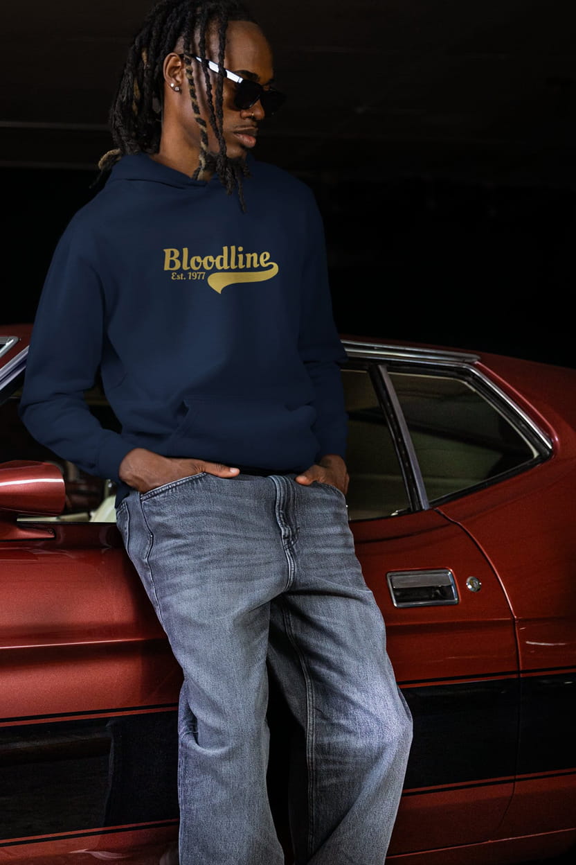 Person wearing a navy hoodie with 'Bloodline' logo, standing next to a red car.