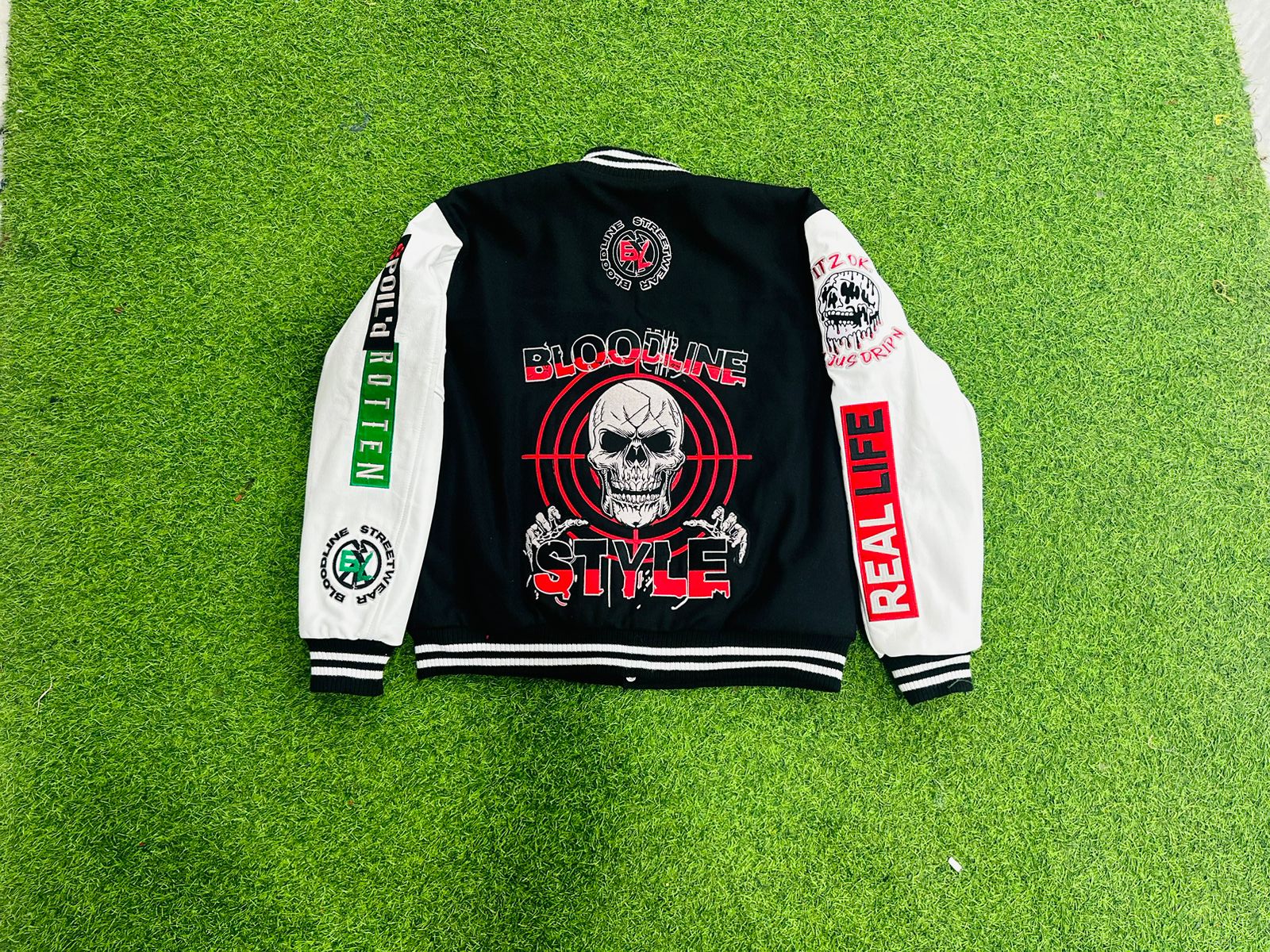Black jacket with white and red designs on a green grass background