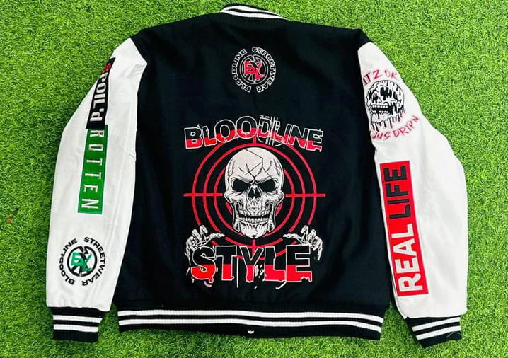 Black and white varsity jacket with graphic designs and text on a grass background