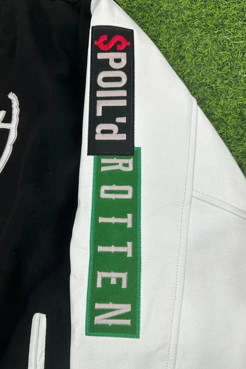 Close-up of a jacket with 'Spoil'd Rotten' branding on a grass background