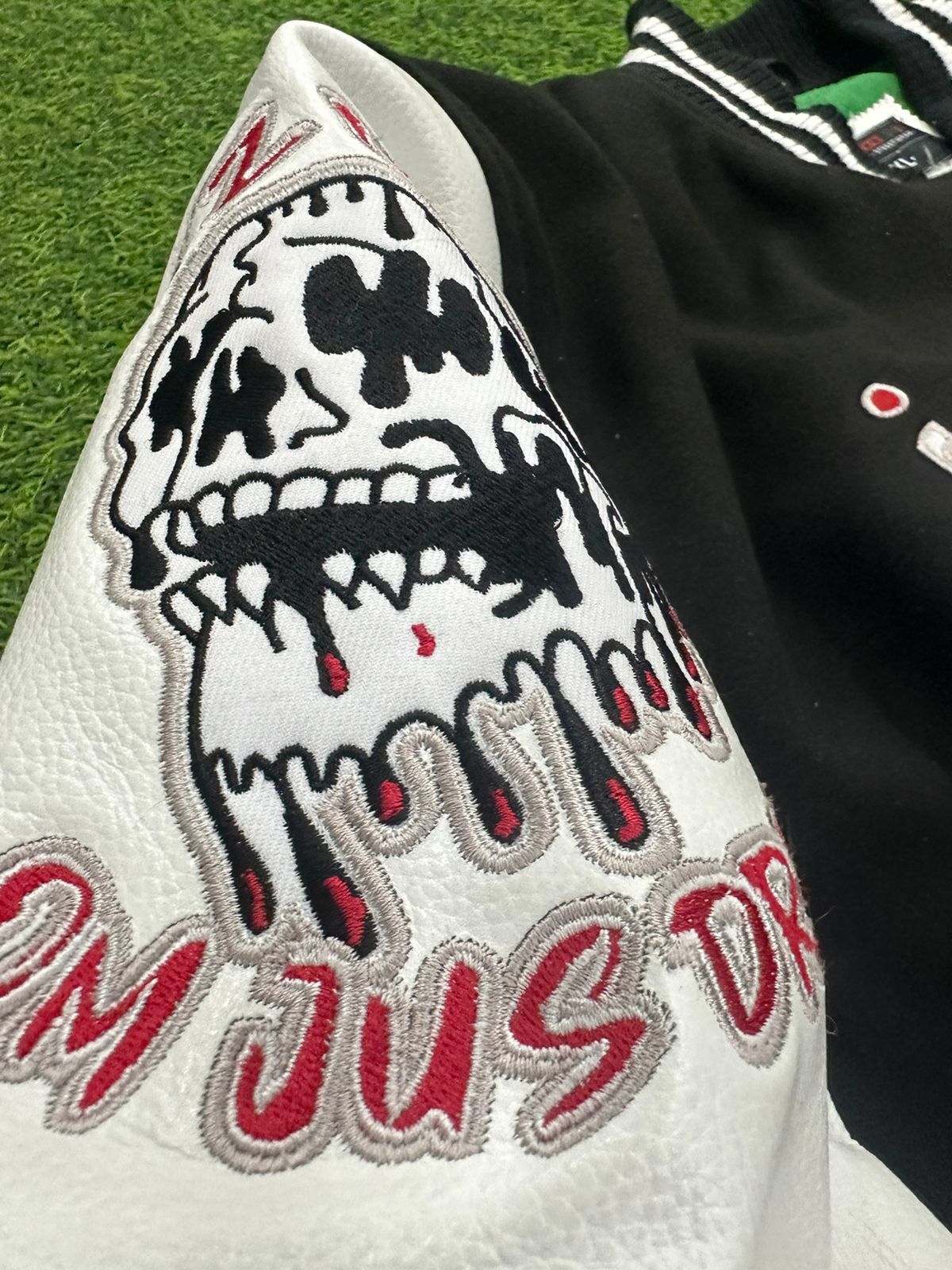 Close-up of a jacket with a skull design and text on a grass background