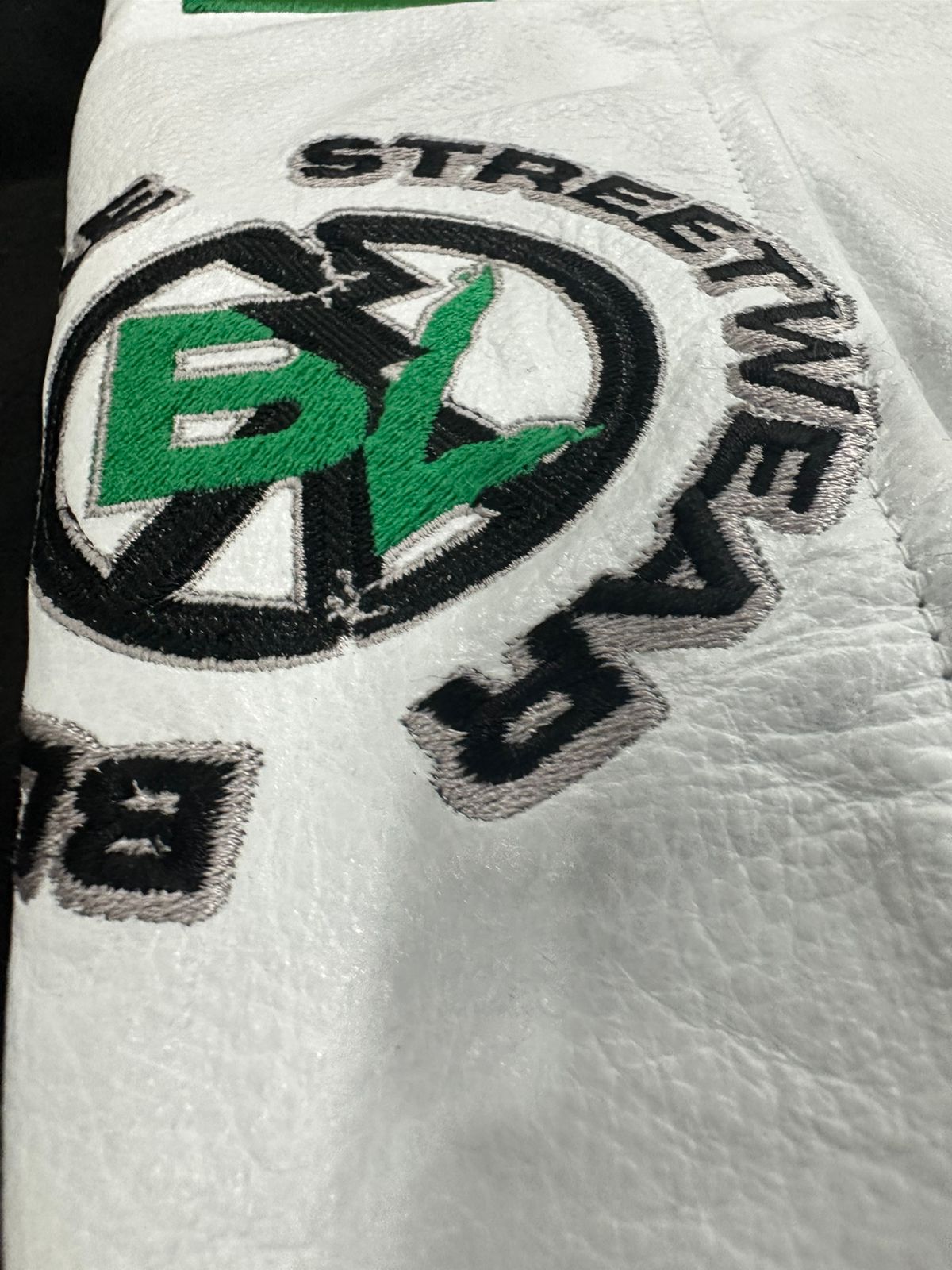 Close-up of a white glove with a logo and text on a black background