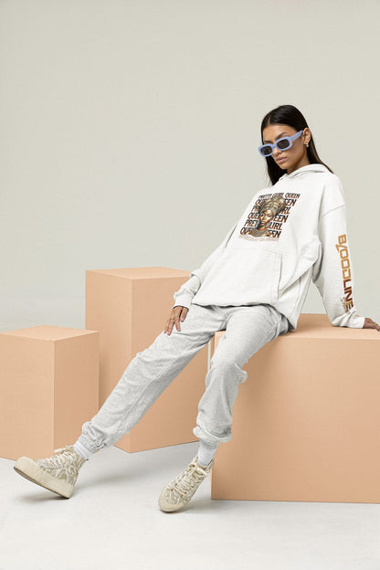 Person wearing a white hoodie with text and graphics, sitting on beige blocks against a light gray background.