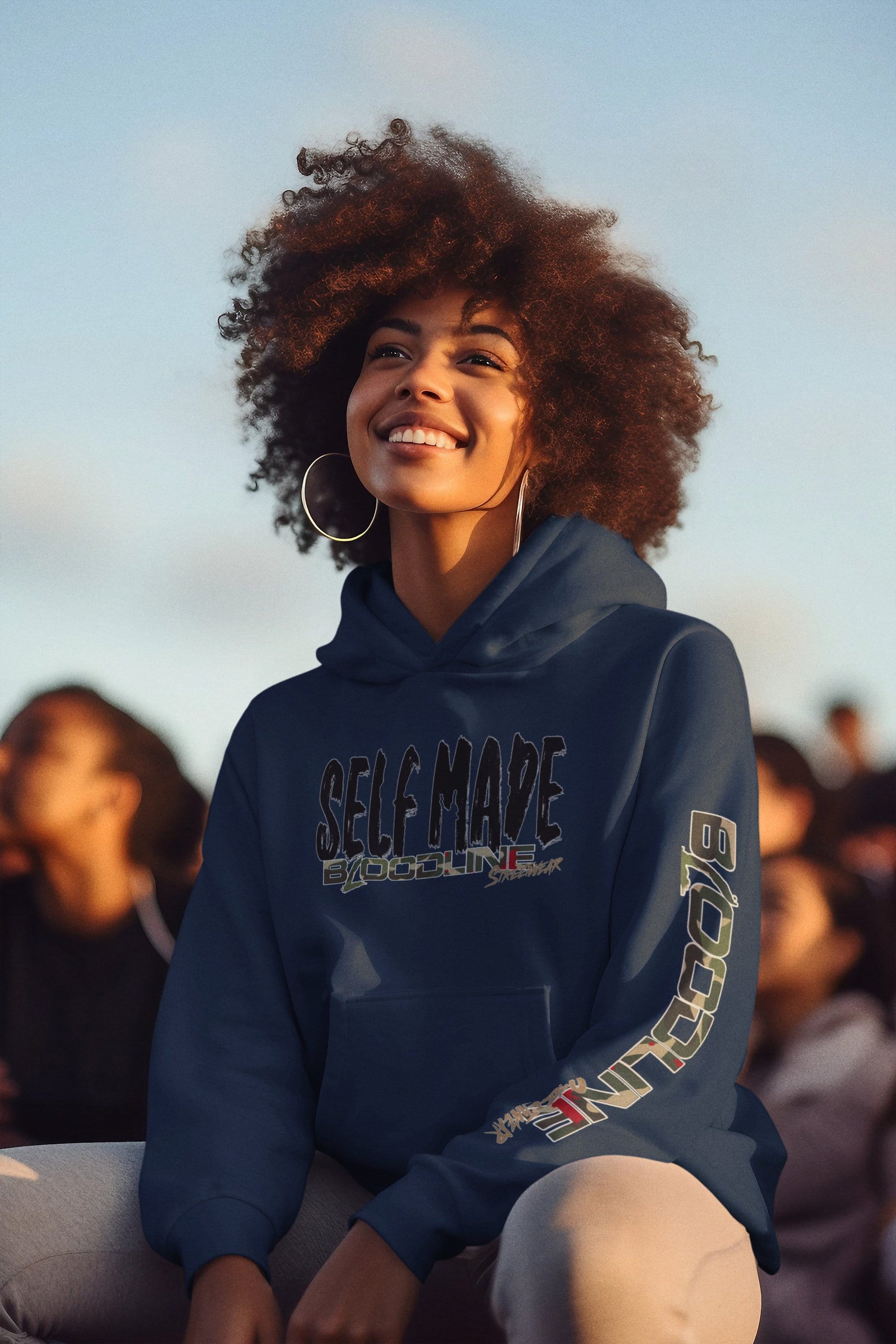 Woman wearing a navy blue hoodie with text, sitting outdoors with a blurred background