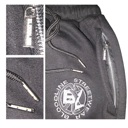 black sweatpants with zipper details and a brand logo on a white background