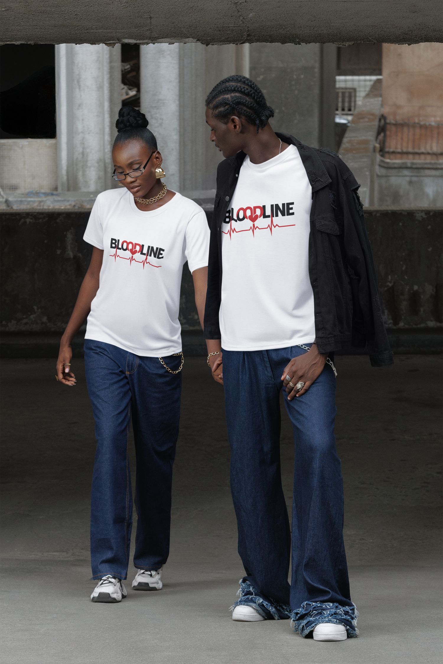 Two people wearing matching white t-shirts with a logo, standing in an urban setting.