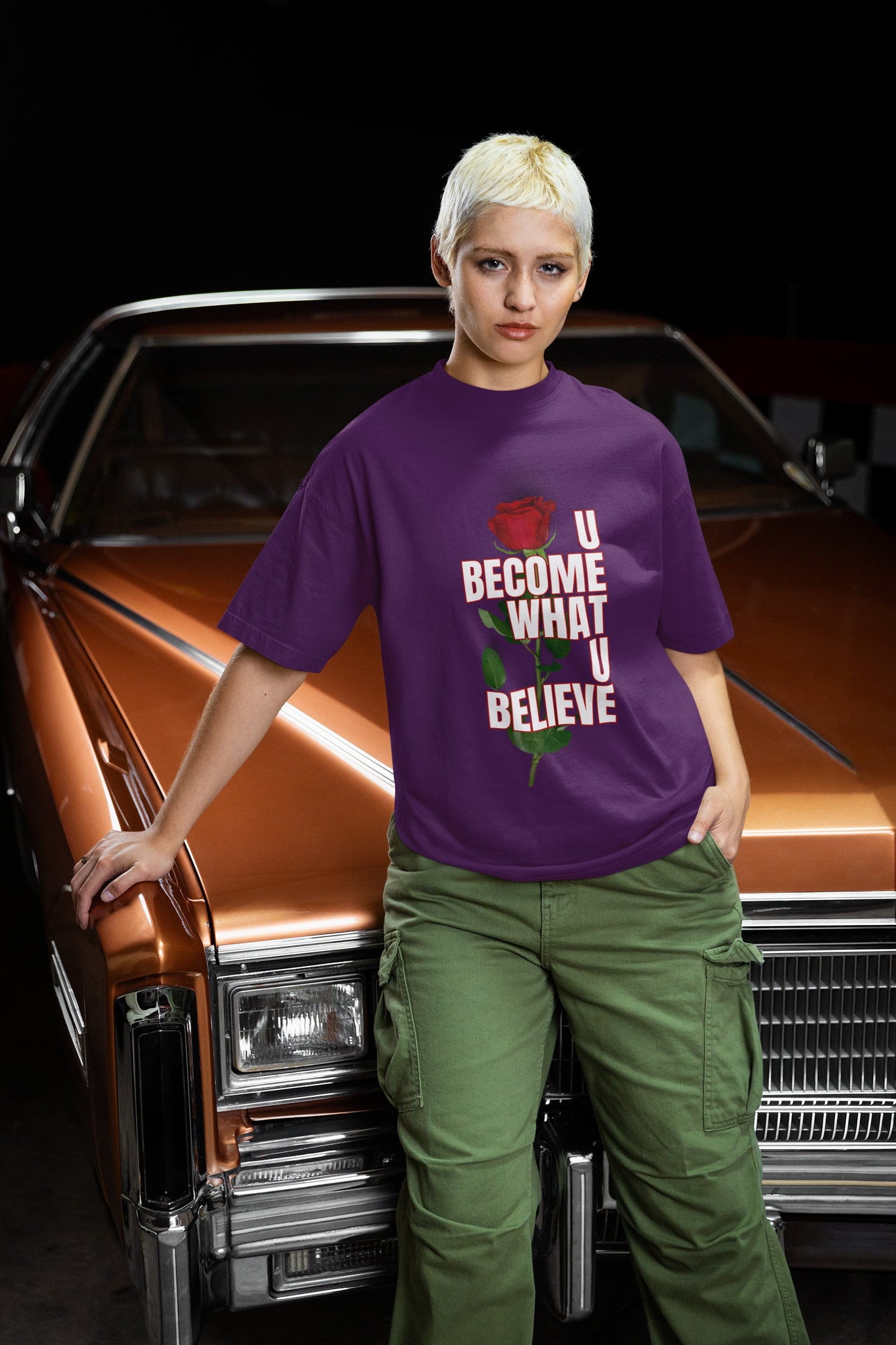 Person wearing a purple t-shirt with motivational text standing in front of a classic car.