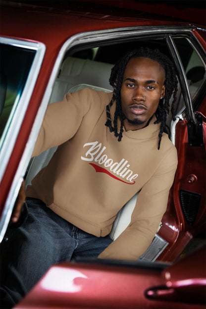 Man sitting in a red car wearing a beige sweatshirt with 'Bloodline' text.