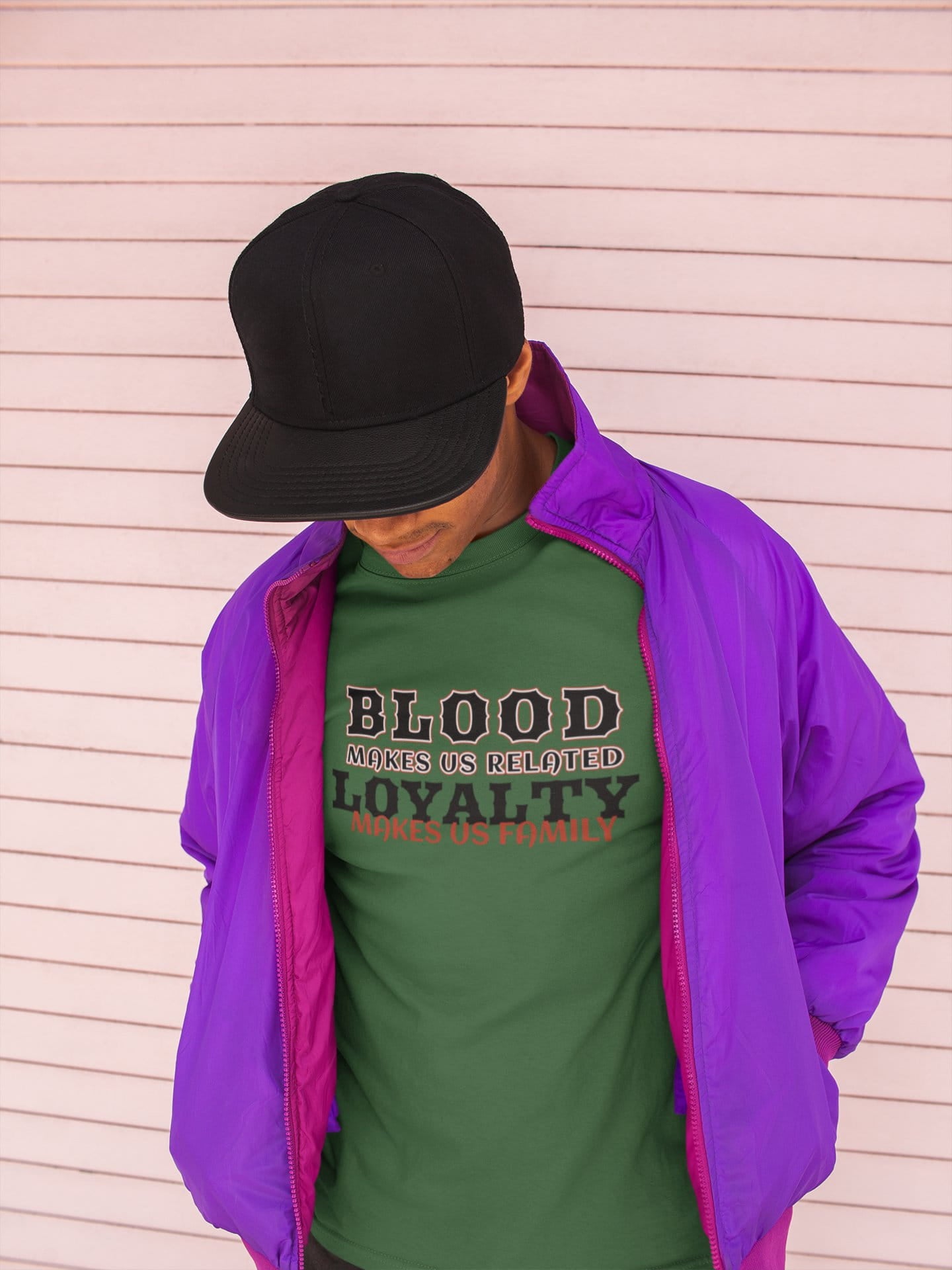 Person wearing a green shirt with text and a purple jacket against a light wooden panel background