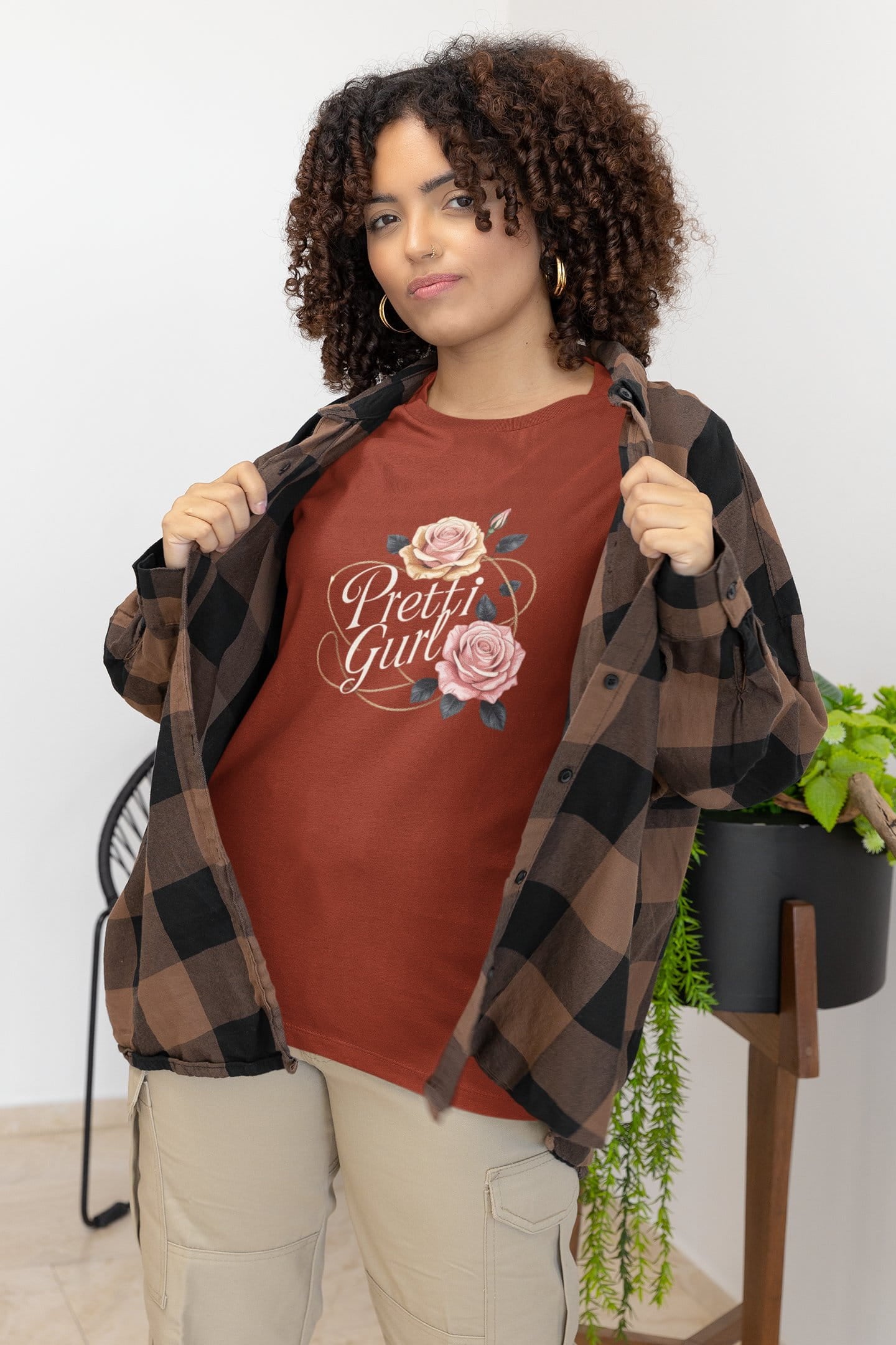 Woman wearing a red 'Pretty Girl' t-shirt with a floral design, standing indoors.