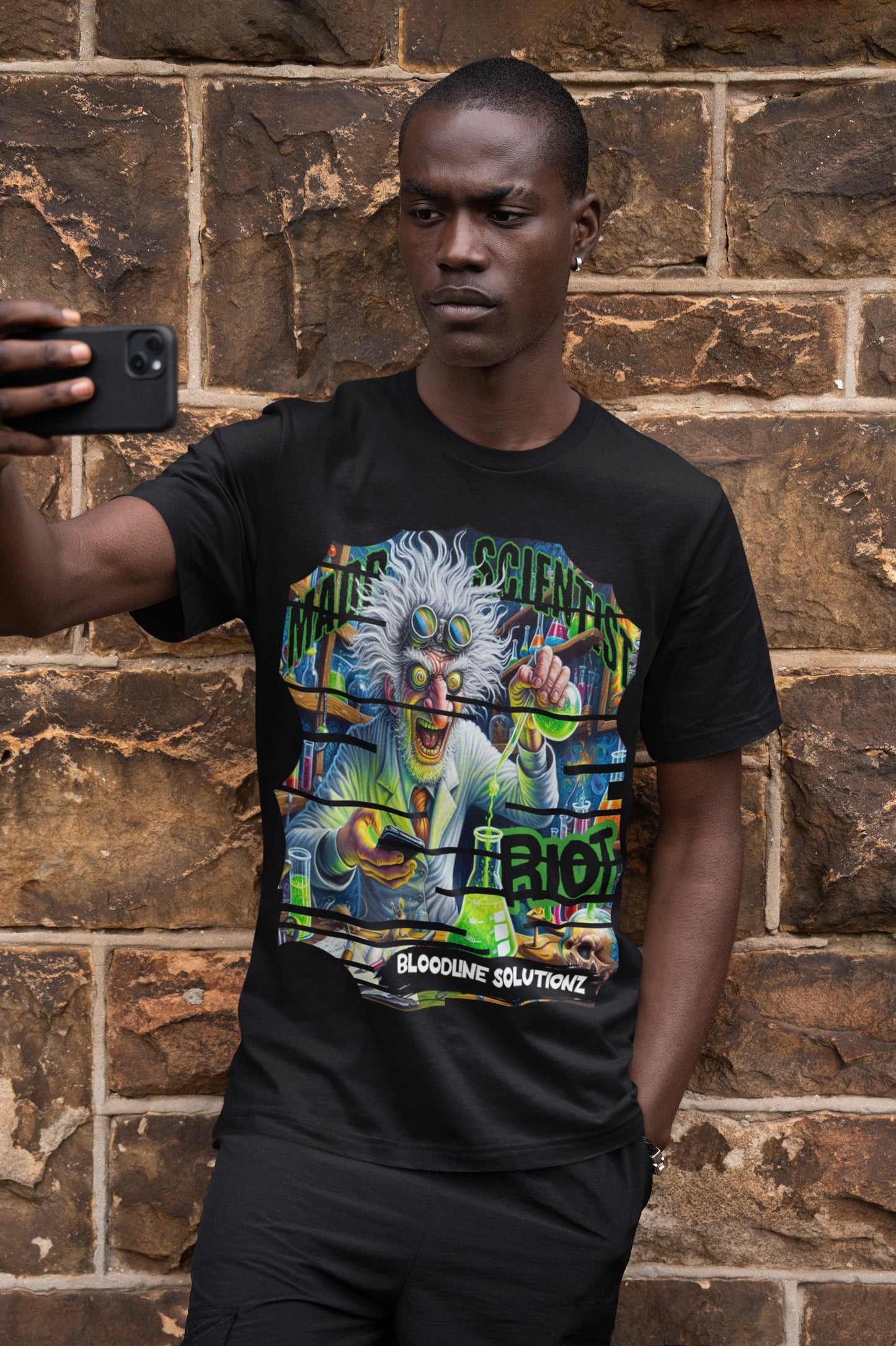 Person wearing a black t-shirt with a colorful graphic design, taking a selfie against a brick wall.