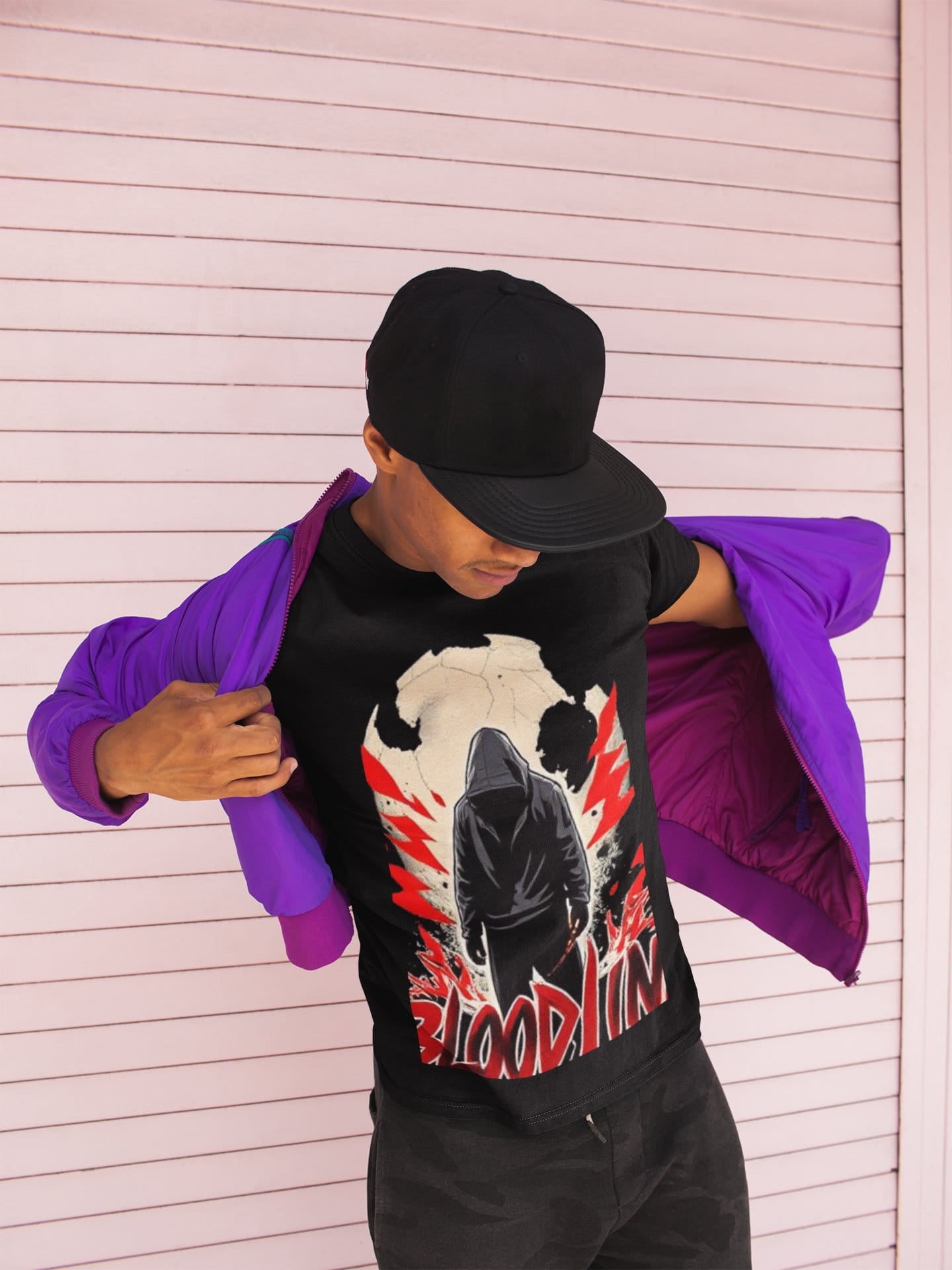 Person wearing a black t-shirt with a graphic design and a purple jacket over their shoulder against a white background.