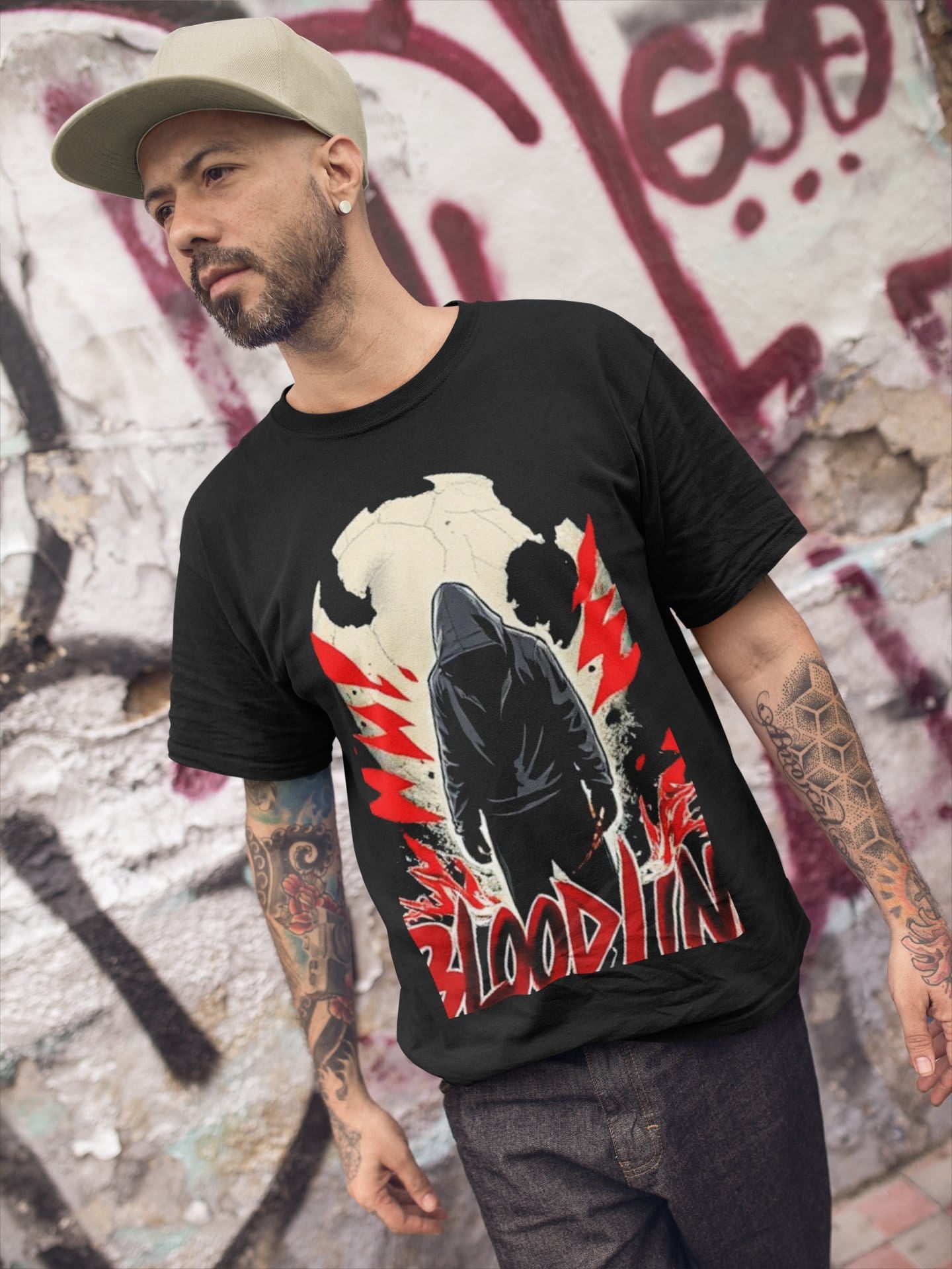 Man wearing a black t-shirt with a graphic design in front of a graffiti-covered wall.