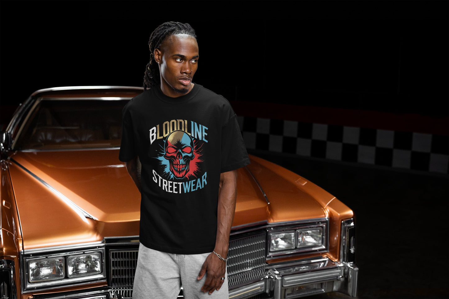 Person wearing a 'Bloodline Streetwear' t-shirt standing next to a classic car with a black background.