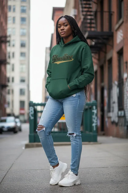 A woman stands on a city sidewalk wearing a dark green pullover hoodie with 'Blindline' written in gold script across the chest, paired with light-wash ripped jeans and white sneakers.