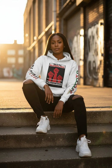 Woman wearing a white hoodie with graphic design sitting on steps outdoors.
