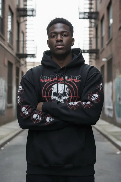 A man wearing a black pullover hoodie with a red and white skull graphic and 'BLOODY DEVILS' text on the chest, standing in an urban alleyway.