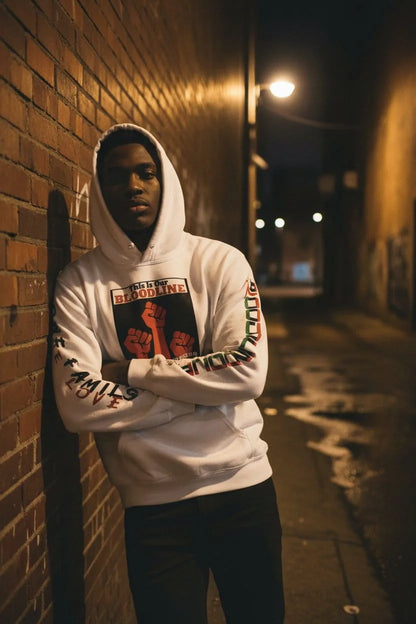 Person wearing a white hoodie with graphic designs in an alleyway at night.