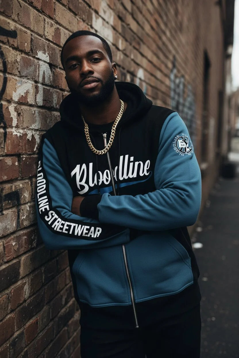 Man wearing a blue and black hoodie with 'Bloodline Streetwear' text against a brick wall.