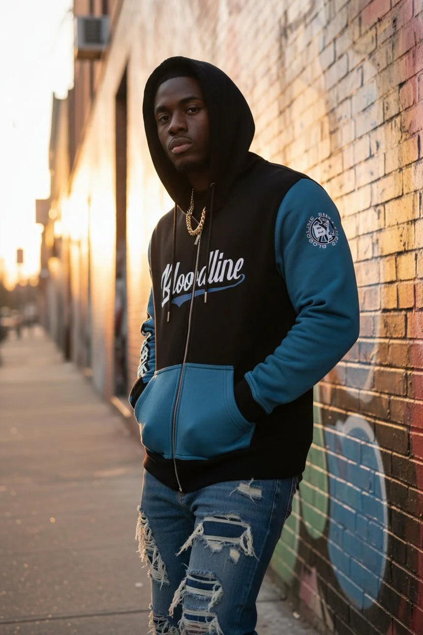 Person wearing a black and blue hoodie with 'Bloodline' text, standing against a graffiti-covered wall.