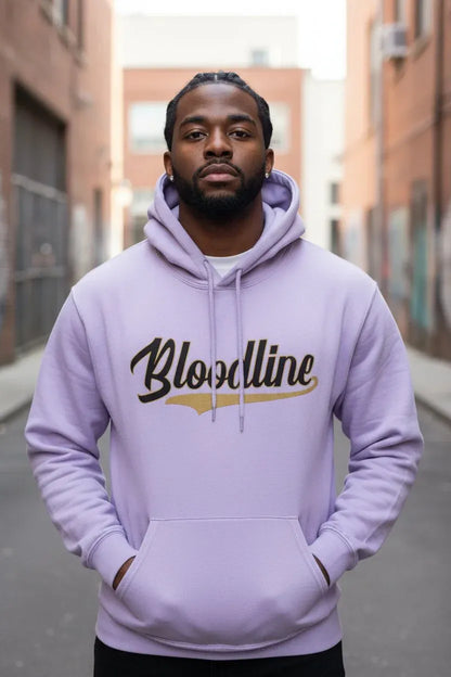 A man wearing a light purple hoodie with 'Bloodline' printed across the chest in black and gold, standing in an outdoor alleyway.