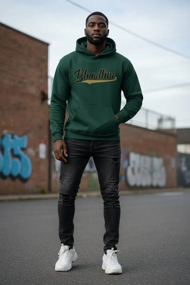 A man wearing a dark green hoodie with 'Blondline' printed across the chest in gold and white, paired with black jeans and white sneakers, standing in an outdoor urban setting.